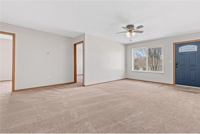 carpeted entrance foyer featuring a ceiling fan, baseboards, and a textured ceiling