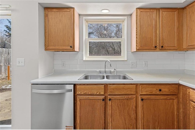 kitchen with dishwasher, light countertops, backsplash, and a sink