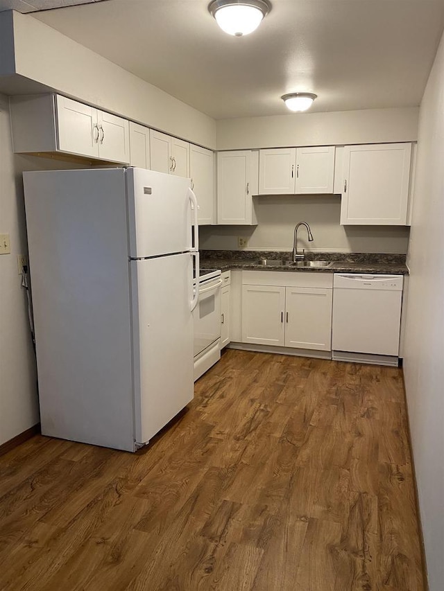 kitchen with a sink, white appliances, dark wood finished floors, and white cabinetry