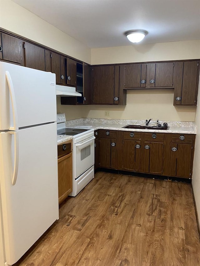 kitchen featuring white appliances, dark wood-style floors, a sink, light countertops, and dark brown cabinets