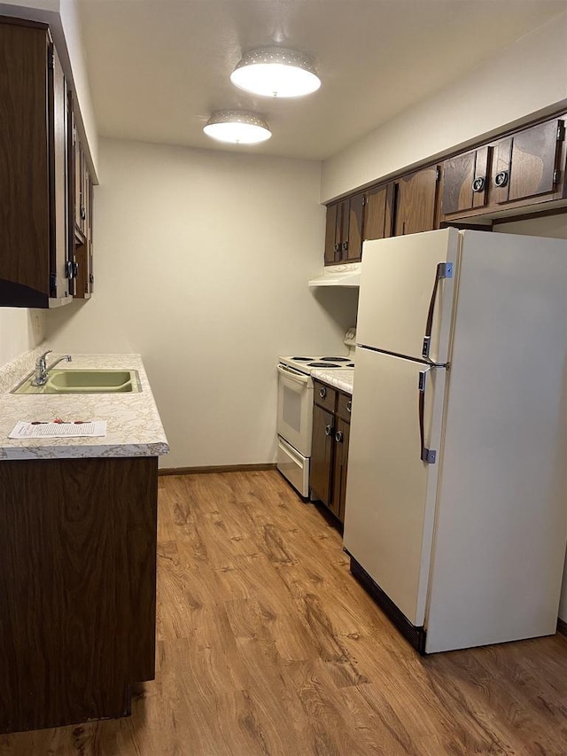 kitchen with a sink, white appliances, and dark brown cabinets