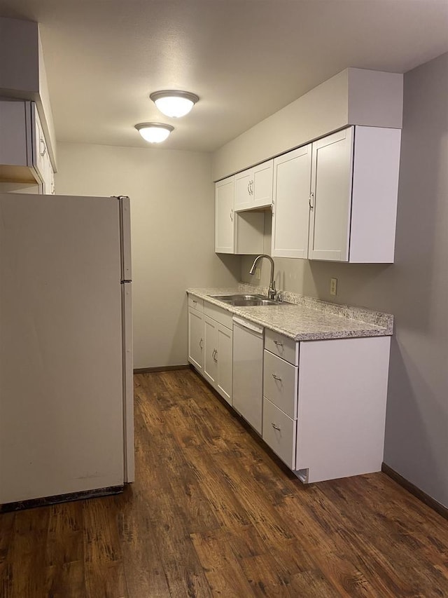 kitchen featuring a sink, baseboards, dark wood finished floors, and freestanding refrigerator