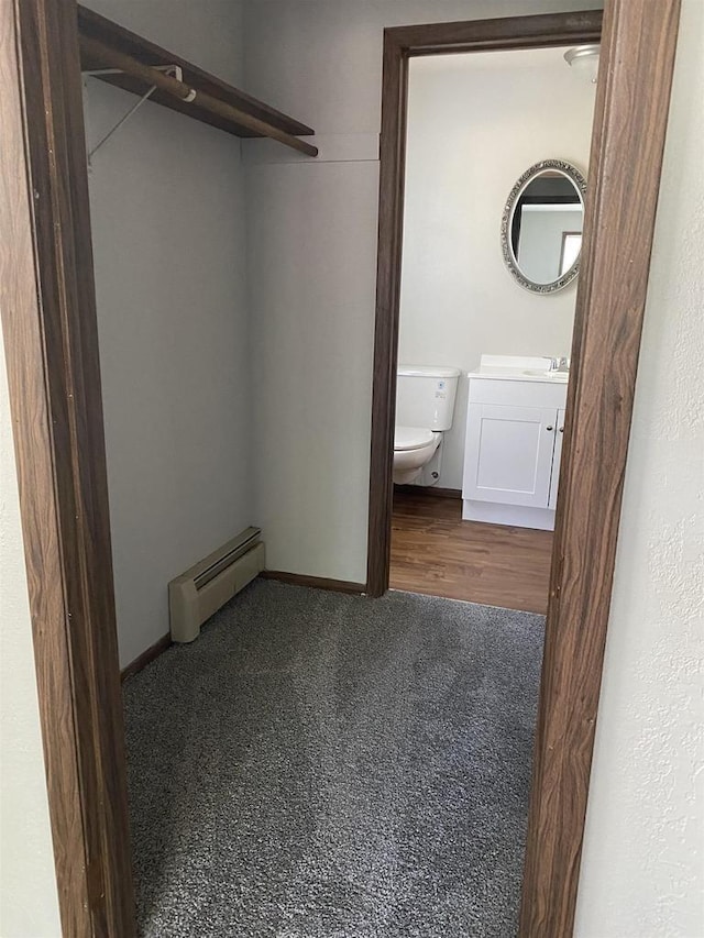 spacious closet with a baseboard heating unit and a sink