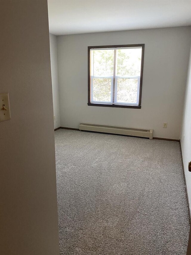 carpeted spare room featuring baseboards and baseboard heating