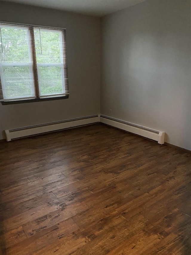 empty room featuring dark wood-style floors and a baseboard heating unit