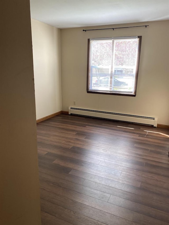 spare room featuring baseboards, dark wood-style flooring, and baseboard heating