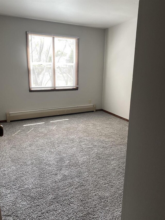 spare room with a baseboard heating unit, baseboards, and carpet floors