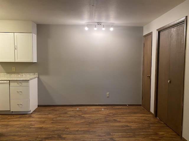 unfurnished dining area with baseboards and dark wood-style floors