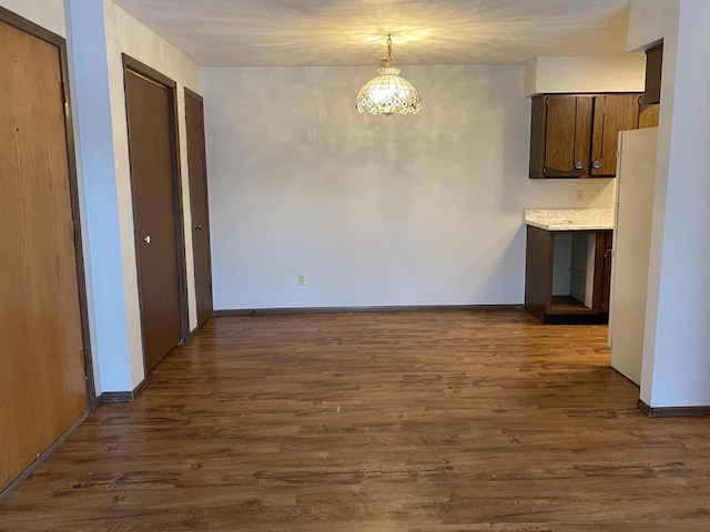 unfurnished dining area with dark wood finished floors and baseboards