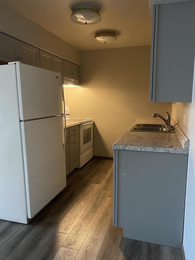 kitchen featuring gray cabinetry, light countertops, dark wood-style floors, white appliances, and a sink