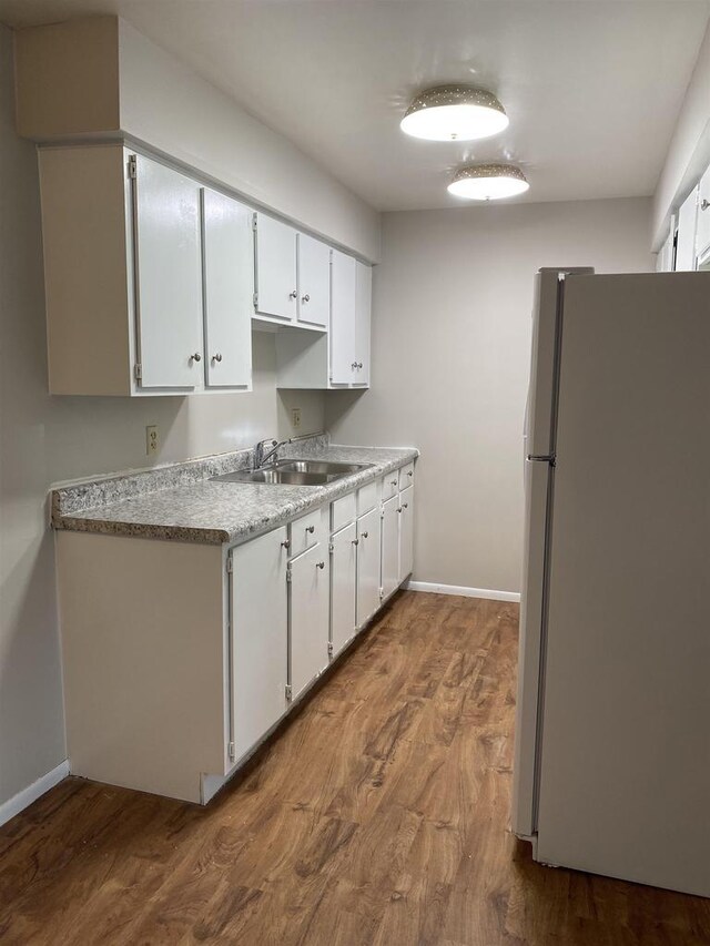 kitchen featuring a sink, dark wood-type flooring, white cabinets, and freestanding refrigerator