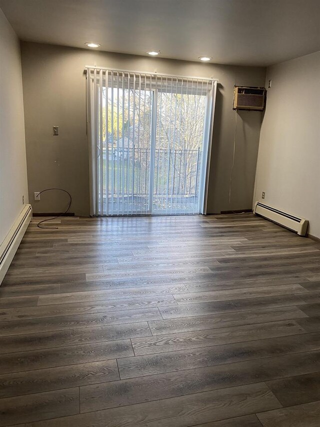 empty room featuring dark wood-type flooring, recessed lighting, a wall mounted air conditioner, and a baseboard radiator