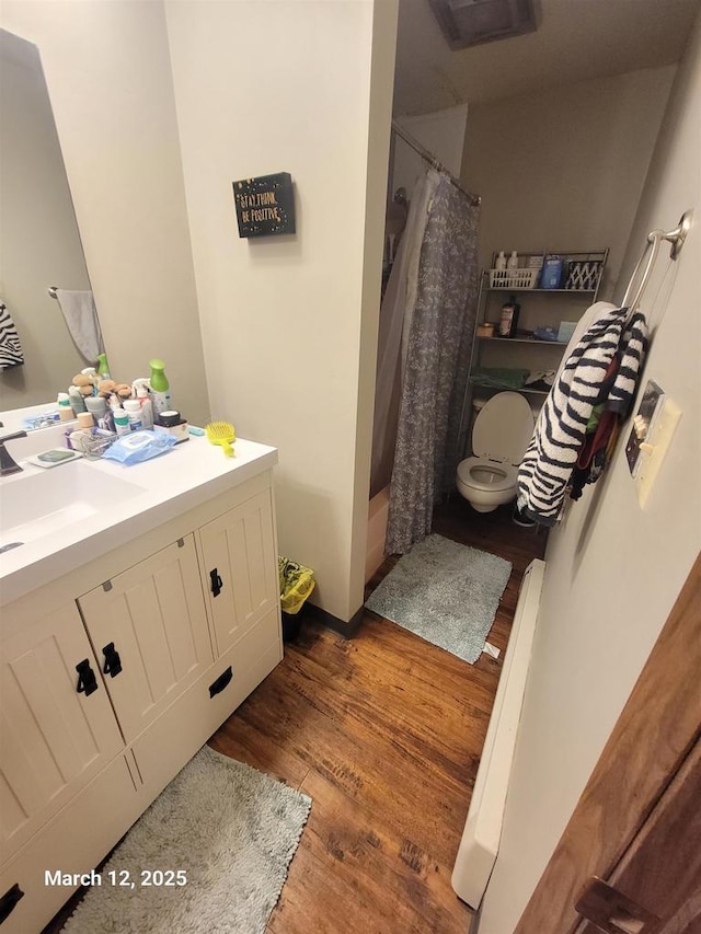 full bath with curtained shower, vanity, toilet, and wood finished floors