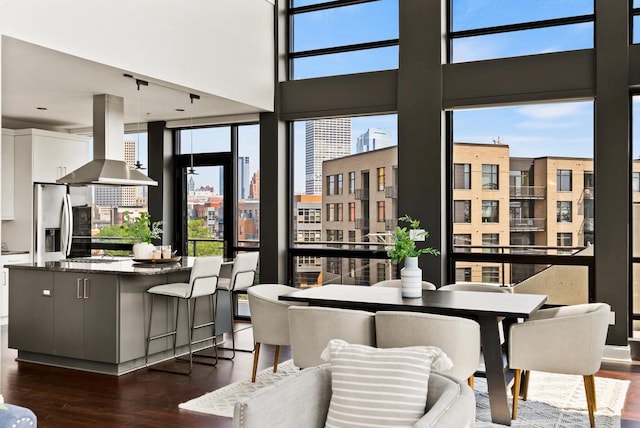 dining space with dark wood-type flooring, a healthy amount of sunlight, and a towering ceiling