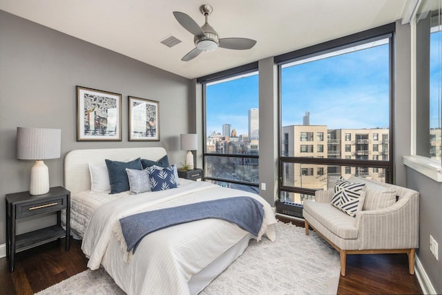 bedroom featuring a city view, wood finished floors, visible vents, and expansive windows