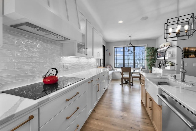 kitchen with a notable chandelier, a sink, stainless steel dishwasher, range hood, and black electric cooktop