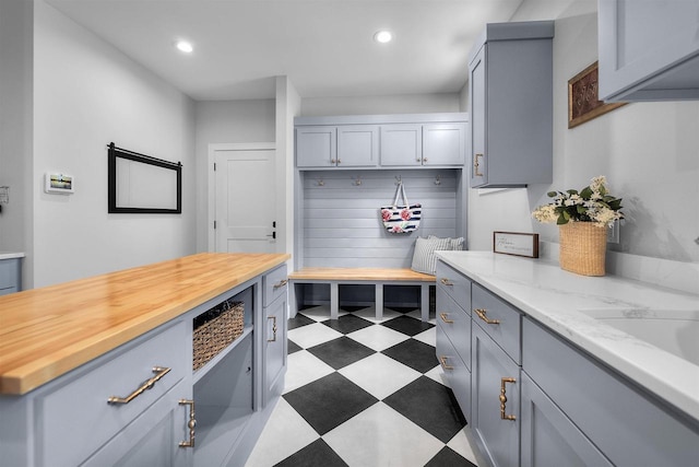 mudroom featuring recessed lighting, light floors, and a sink