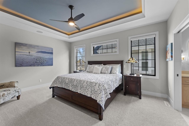 bedroom featuring a tray ceiling, baseboards, and light colored carpet