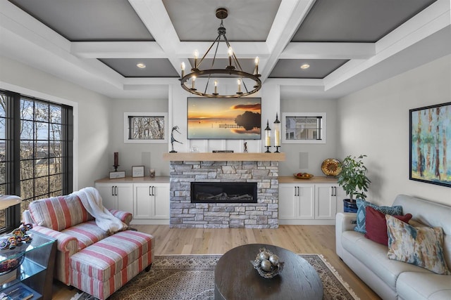 living room with a notable chandelier, coffered ceiling, a fireplace, and light wood-style floors