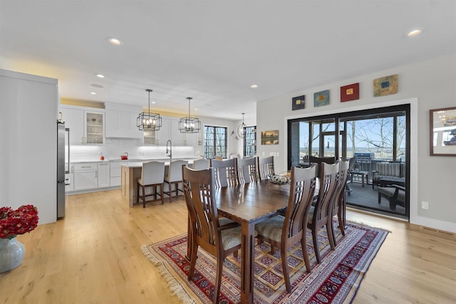 dining room featuring baseboards, recessed lighting, light wood-type flooring, and a chandelier