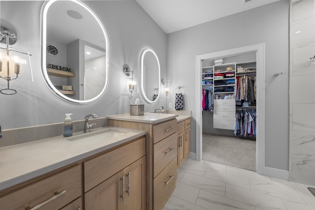 bathroom with a spacious closet, marble finish floor, two vanities, and a sink