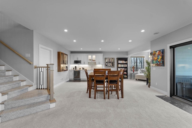 dining area featuring baseboards, beverage cooler, light colored carpet, stairs, and recessed lighting