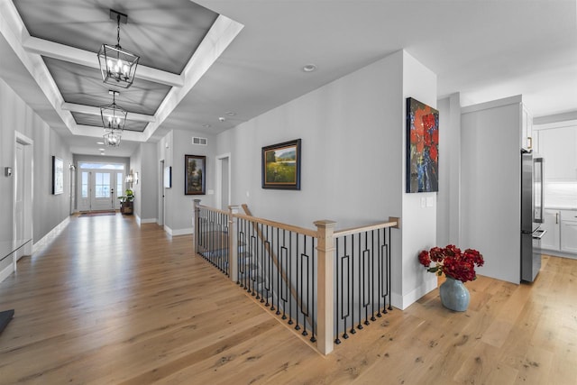 hallway with visible vents, an upstairs landing, a notable chandelier, light wood finished floors, and baseboards