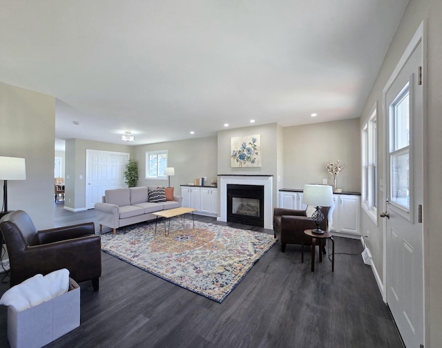 living room with dark wood finished floors, plenty of natural light, baseboards, and a fireplace with flush hearth