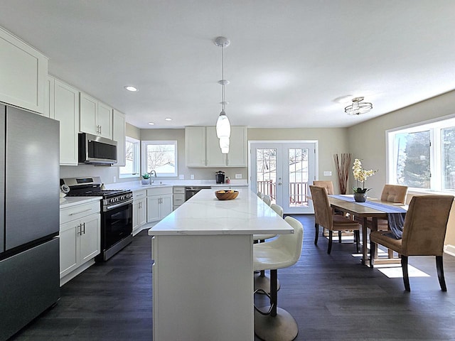 kitchen with a breakfast bar area, a sink, stainless steel appliances, french doors, and a center island