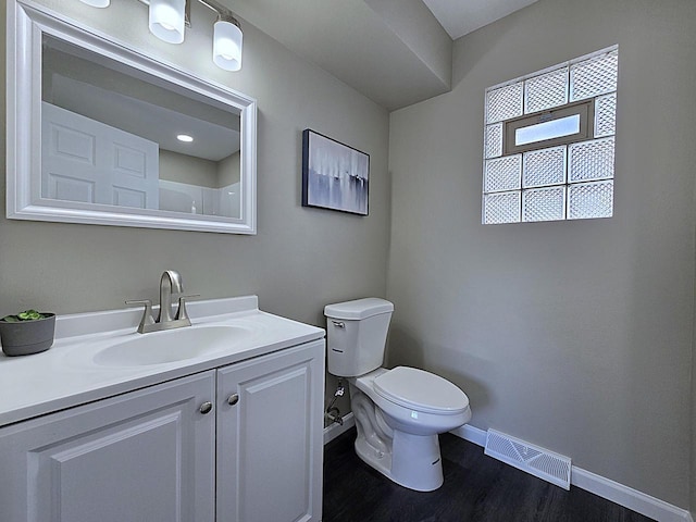 bathroom featuring visible vents, toilet, wood finished floors, baseboards, and vanity