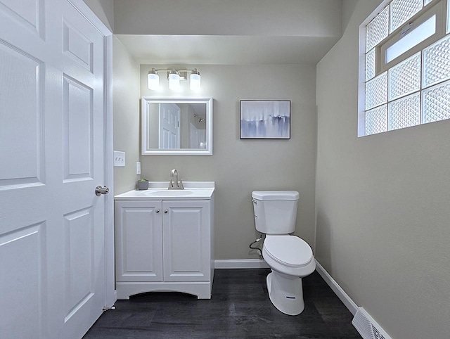 bathroom with vanity, toilet, wood finished floors, and baseboards