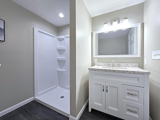 bathroom featuring a stall shower, baseboards, wood finished floors, and vanity