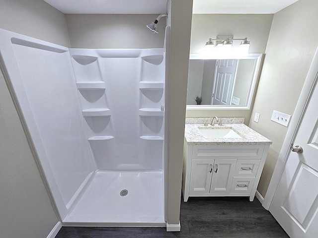 full bath with vanity, a shower stall, wood finished floors, and baseboards