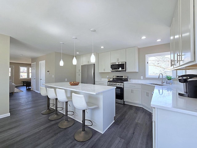 kitchen featuring a center island, dark wood-type flooring, appliances with stainless steel finishes, white cabinetry, and a sink