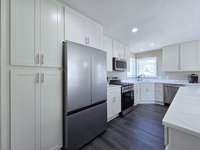 kitchen featuring appliances with stainless steel finishes, white cabinetry, and a sink