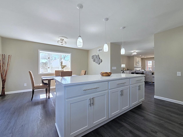 kitchen with baseboards, a kitchen island, dark wood-type flooring, and light countertops