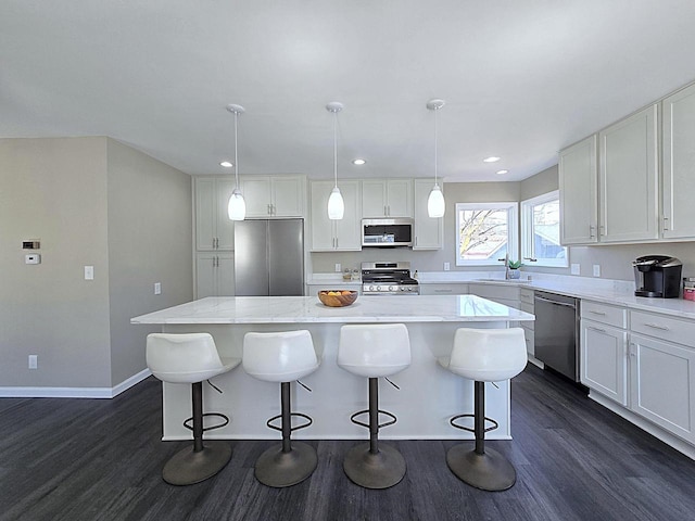 kitchen with a kitchen island, dark wood-type flooring, appliances with stainless steel finishes, white cabinetry, and a sink