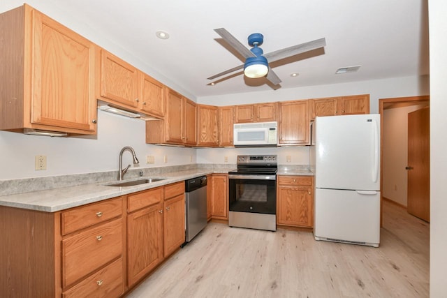 kitchen featuring visible vents, a sink, stainless steel appliances, light wood finished floors, and light countertops