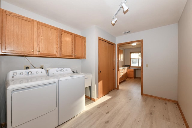 clothes washing area with visible vents, baseboards, light wood-type flooring, cabinet space, and independent washer and dryer