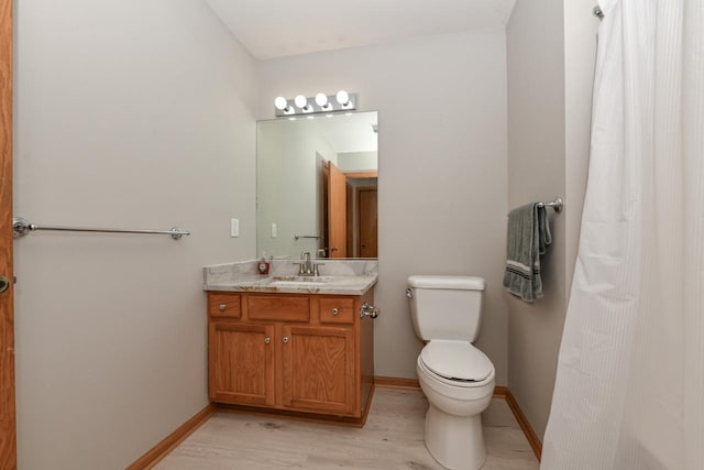 bathroom featuring toilet, vanity, baseboards, and wood finished floors