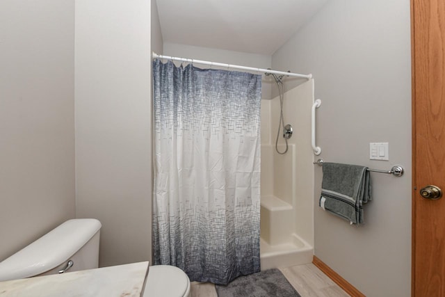 full bathroom featuring curtained shower, baseboards, toilet, and wood finished floors