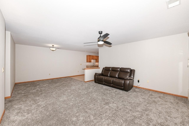 sitting room featuring a ceiling fan, baseboards, and light carpet