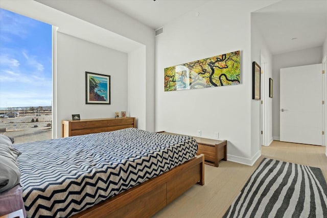 bedroom featuring visible vents, light wood-style flooring, and baseboards