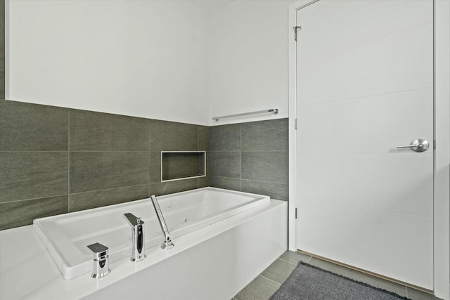 bathroom featuring tile patterned floors, a tub with jets, and tile walls