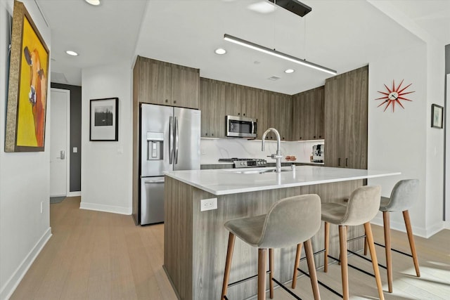 kitchen featuring modern cabinets, a sink, tasteful backsplash, stainless steel appliances, and light countertops