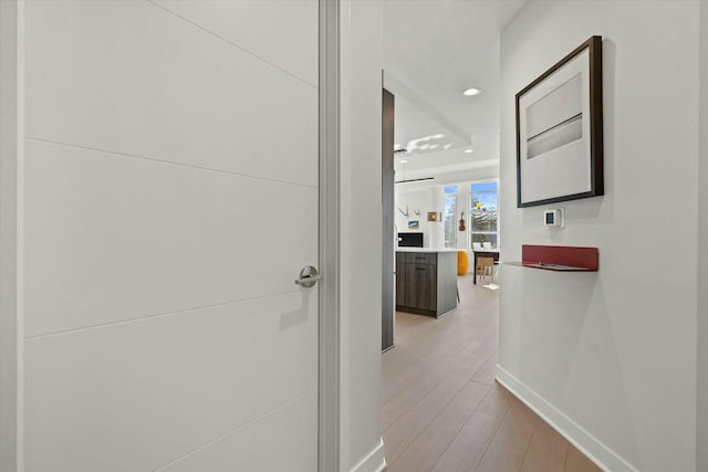 hallway featuring recessed lighting, baseboards, and light wood-type flooring