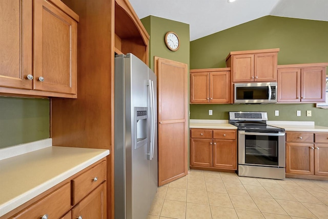 kitchen with brown cabinets, appliances with stainless steel finishes, light countertops, and lofted ceiling