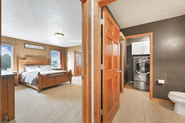 bedroom with a walk in closet, baseboards, light tile patterned floors, light carpet, and washer / clothes dryer