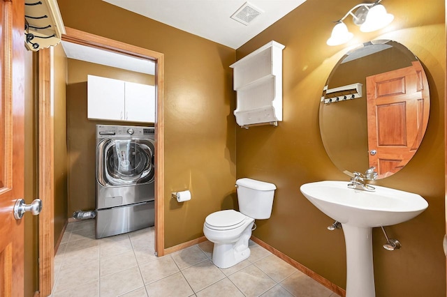 bathroom featuring baseboards, toilet, washer / dryer, and tile patterned flooring