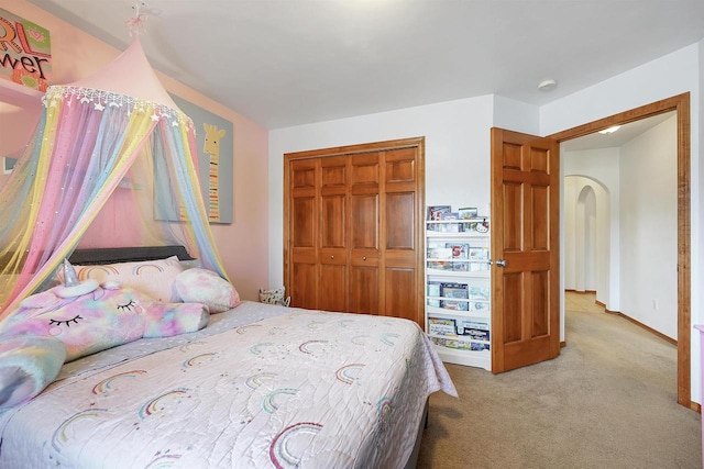 carpeted bedroom featuring a closet and baseboards